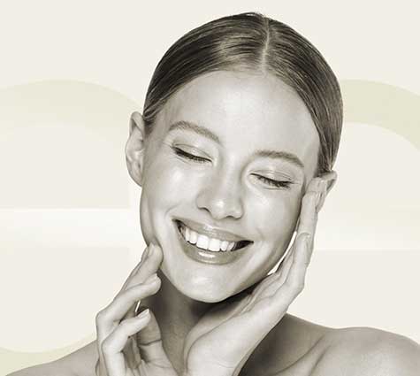 Lächelnde Frau berührt ihr Gesicht – Lipofilling in Tübingen